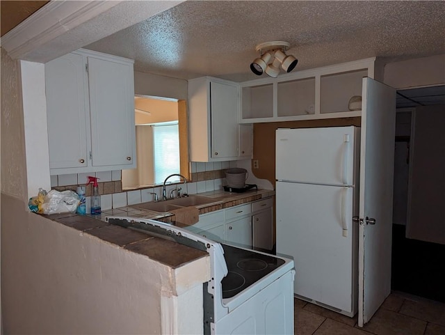 kitchen featuring white fridge, tasteful backsplash, and white cabinetry