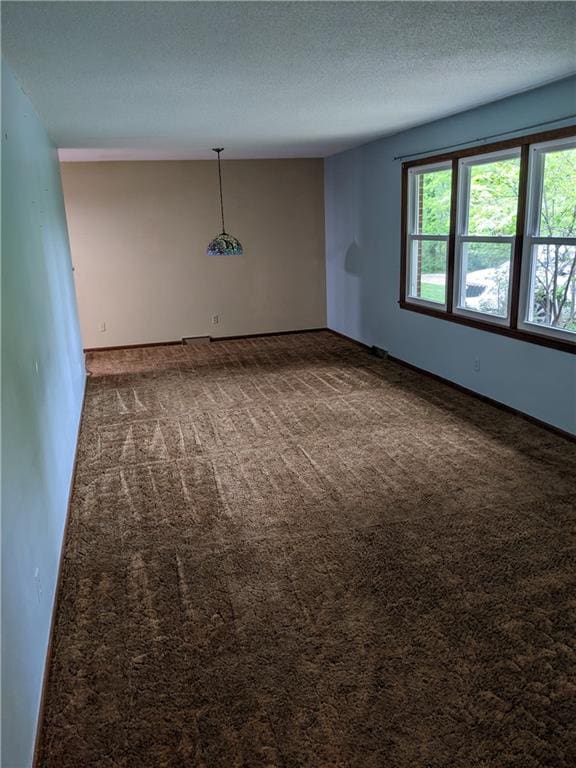 empty room featuring a textured ceiling and dark colored carpet