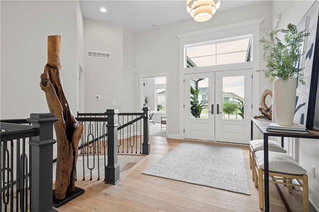 entrance foyer with a high ceiling, light wood-type flooring, and french doors