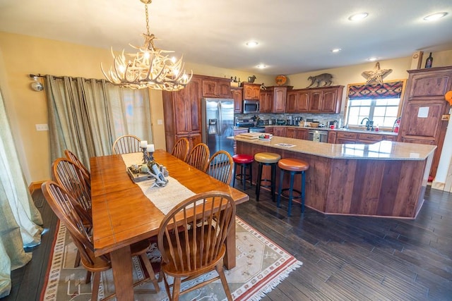 dining space featuring a notable chandelier, sink, and dark wood-type flooring