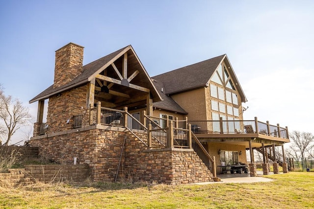 rear view of property featuring a patio area, a wooden deck, and a lawn