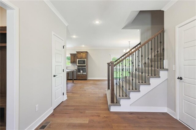 entrance foyer featuring a chandelier, ornamental molding, and wood-type flooring