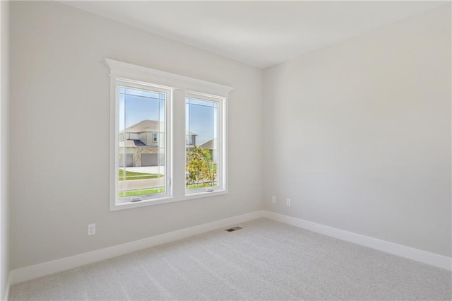 carpeted spare room featuring visible vents and baseboards