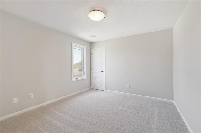 carpeted spare room featuring visible vents and baseboards