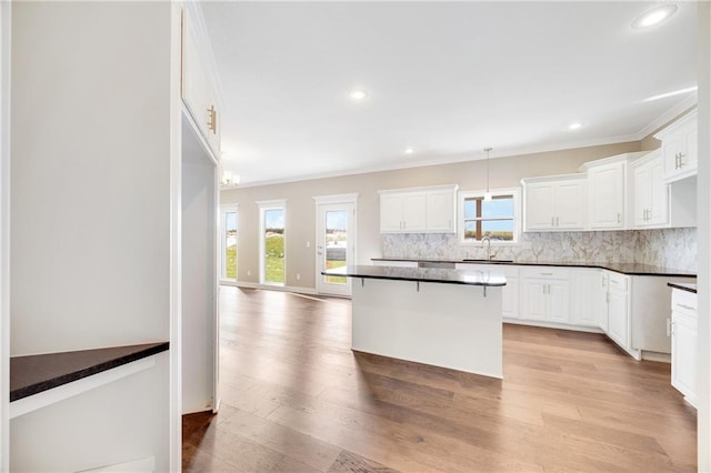 kitchen featuring white cabinets, a breakfast bar, light hardwood / wood-style floors, and tasteful backsplash