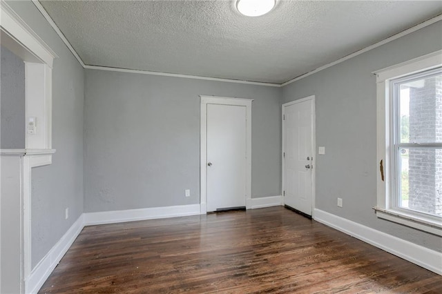 empty room with a textured ceiling, dark hardwood / wood-style floors, and crown molding