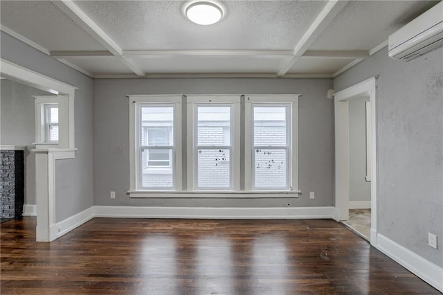 unfurnished room featuring dark wood-type flooring, a textured ceiling, and a wall mounted air conditioner