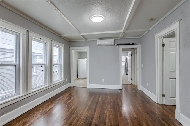 spare room with an AC wall unit, coffered ceiling, a textured ceiling, and dark wood-type flooring