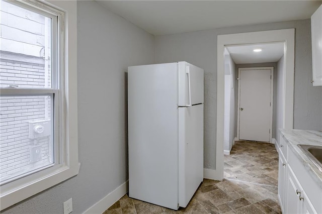 kitchen with white cabinetry, white fridge, and light tile floors