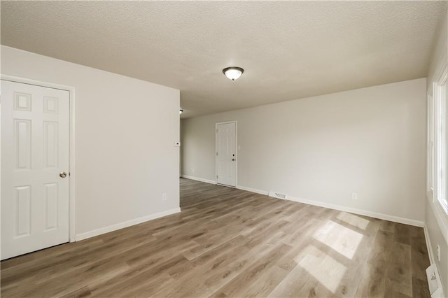 unfurnished room with hardwood / wood-style flooring and a textured ceiling