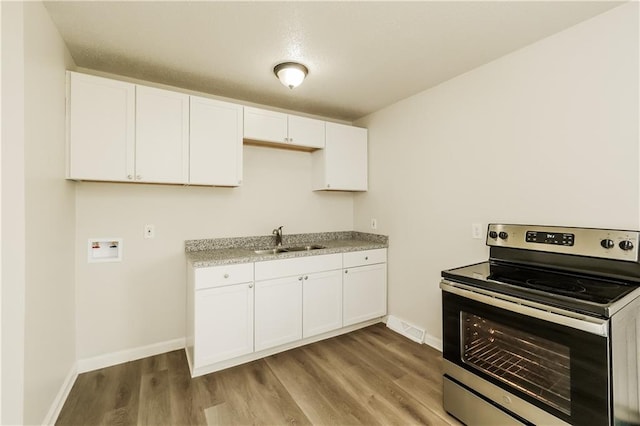 kitchen with light stone countertops, white cabinetry, sink, light hardwood / wood-style floors, and electric range