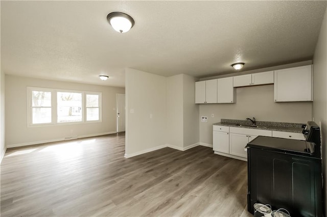 kitchen with sink, a textured ceiling, white cabinetry, hardwood / wood-style floors, and range with electric cooktop