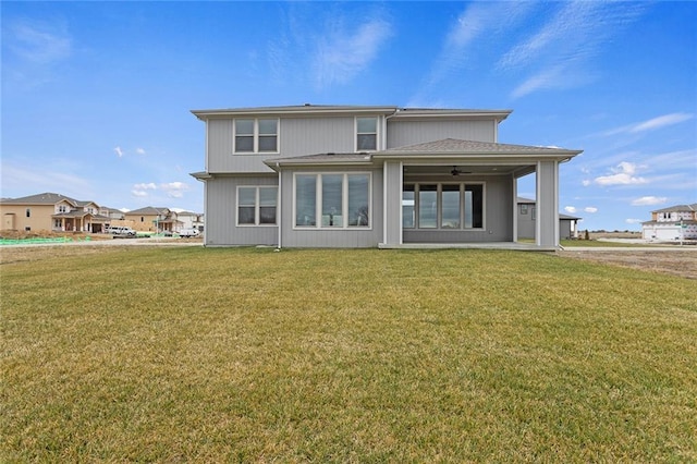 rear view of property with ceiling fan and a yard