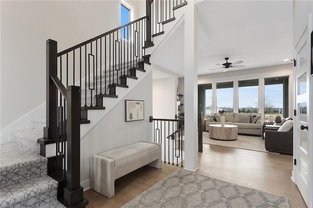 stairway with ceiling fan and wood-type flooring