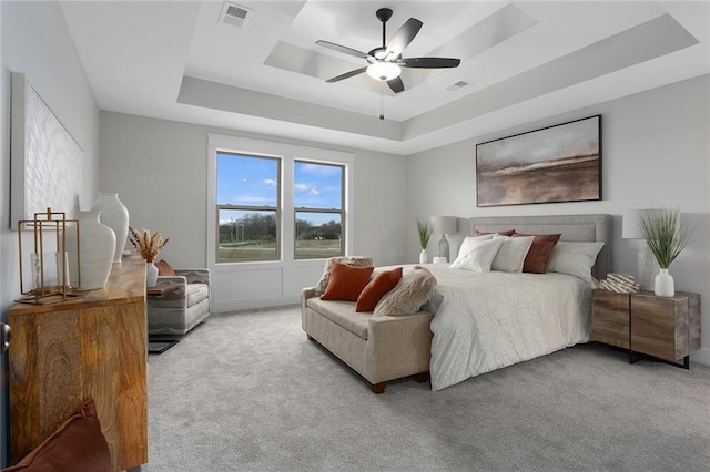 carpeted bedroom featuring a raised ceiling and ceiling fan