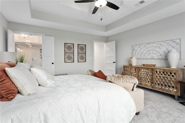 bedroom with light colored carpet, ceiling fan, and a tray ceiling