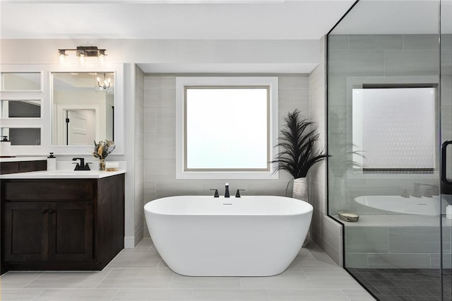 bathroom featuring tile patterned floors, vanity, tile walls, and independent shower and bath