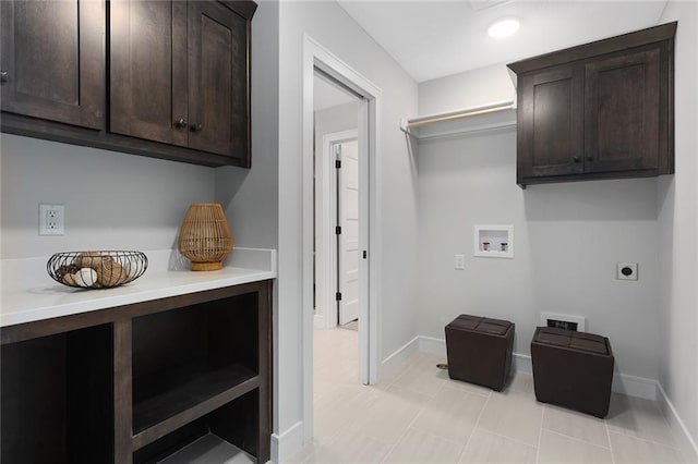 laundry room featuring electric dryer hookup, light tile patterned floors, cabinets, and washer hookup