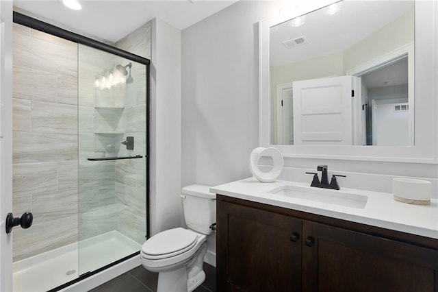 bathroom with tile patterned flooring, vanity, a shower with shower door, and toilet