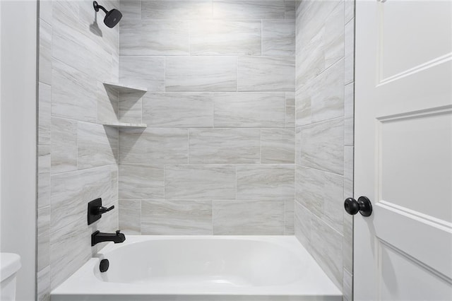 bathroom featuring toilet and tiled shower / bath