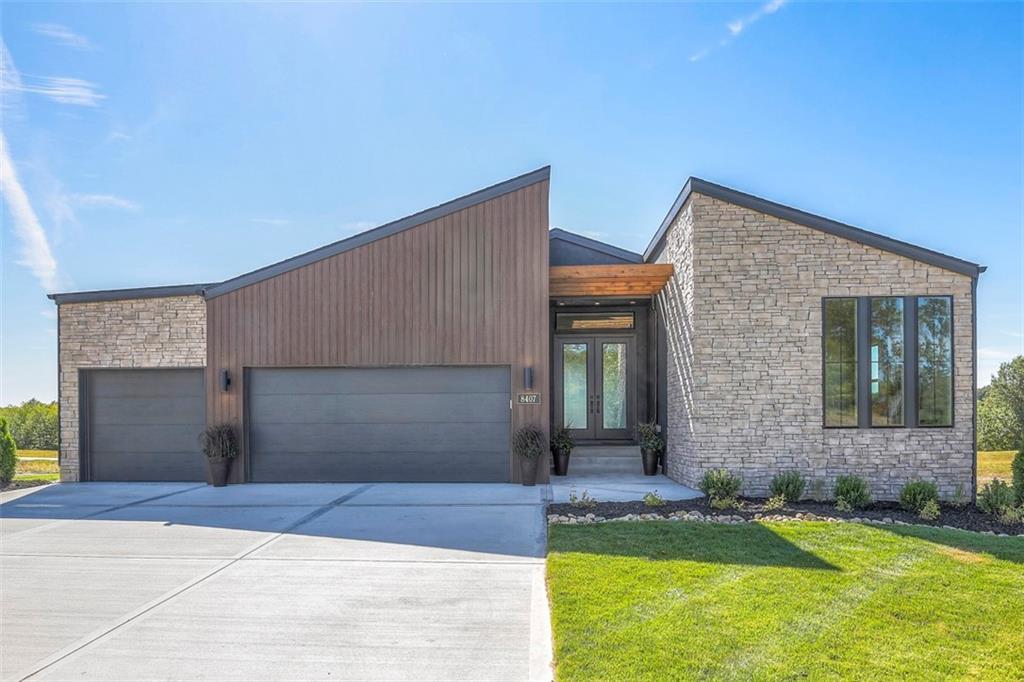 8407 NW 90th St, Kansas City, MO 64153 - view of front of property with a front yard, stone siding, french doors, concrete driveway, and an attached garage