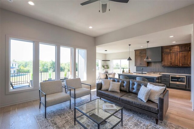 living room with light hardwood / wood-style floors, sink, and ceiling fan