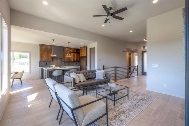 living room with ceiling fan, light wood-type flooring, and sink