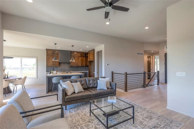 living room featuring light wood-type flooring, sink, and ceiling fan