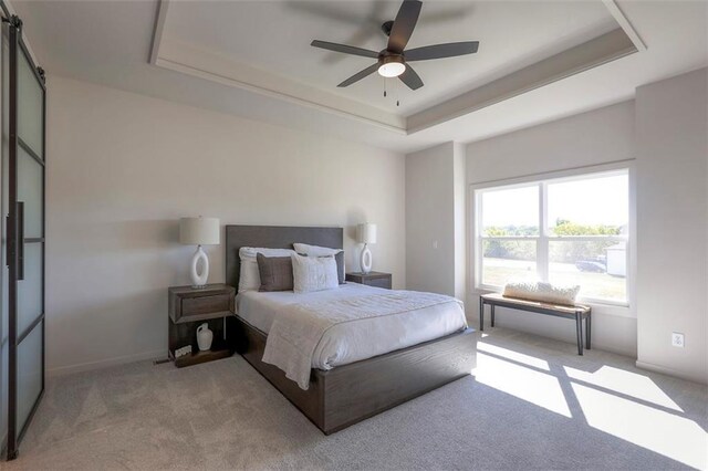 carpeted bedroom with a raised ceiling and ceiling fan