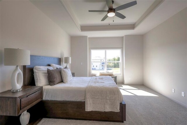 carpeted bedroom with a tray ceiling and ceiling fan