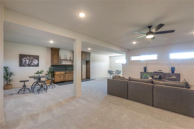 living room featuring ceiling fan, light colored carpet, and sink