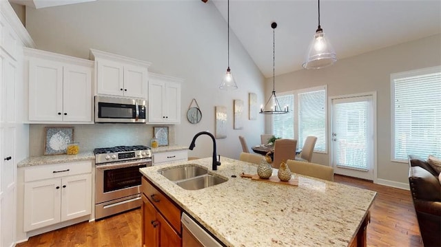 kitchen featuring a kitchen island with sink, stainless steel appliances, sink, tasteful backsplash, and light hardwood / wood-style floors