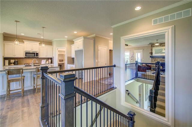 interior space with hardwood / wood-style floors, sink, and ornamental molding