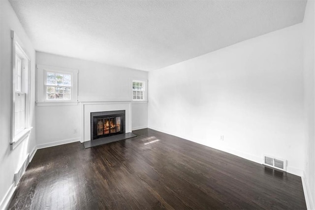 unfurnished living room featuring a textured ceiling and dark hardwood / wood-style flooring