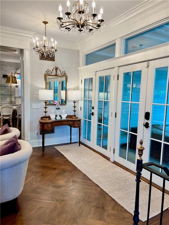 interior space with french doors, parquet floors, a notable chandelier, and ornamental molding