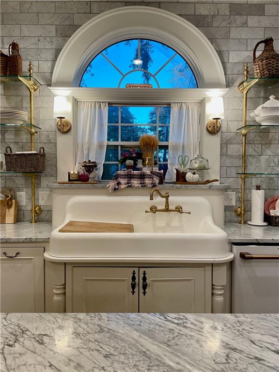 kitchen featuring light stone countertops, dishwasher, and white cabinetry