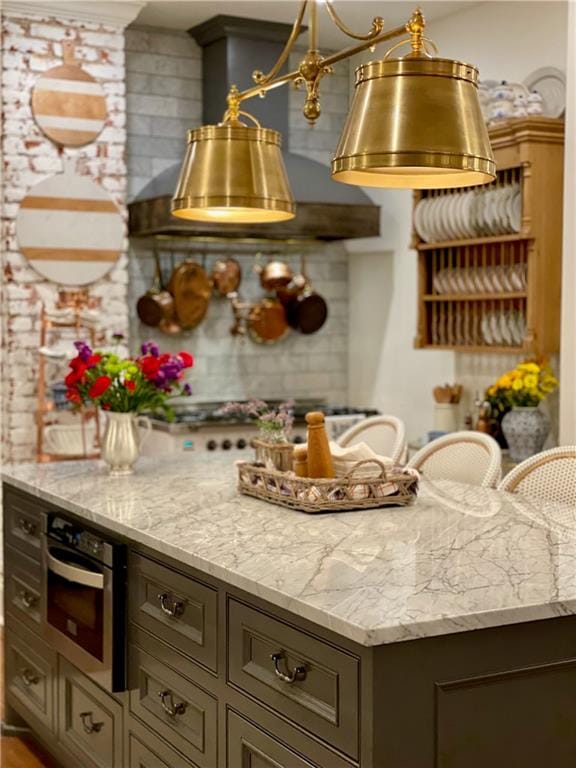 kitchen with oven, light stone counters, and pendant lighting