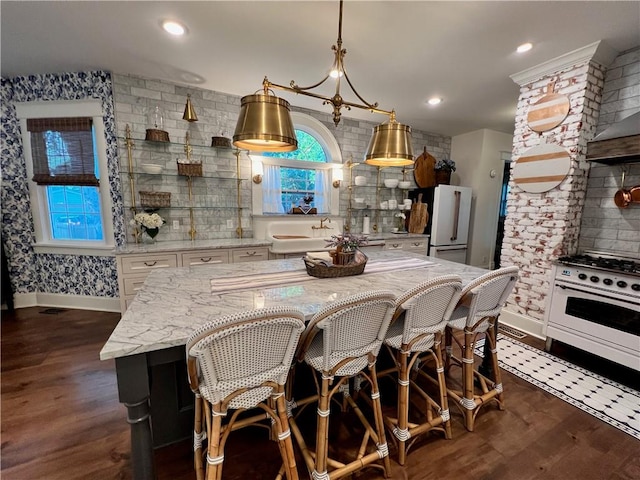 kitchen with light stone countertops, white appliances, dark wood-type flooring, white cabinetry, and pendant lighting