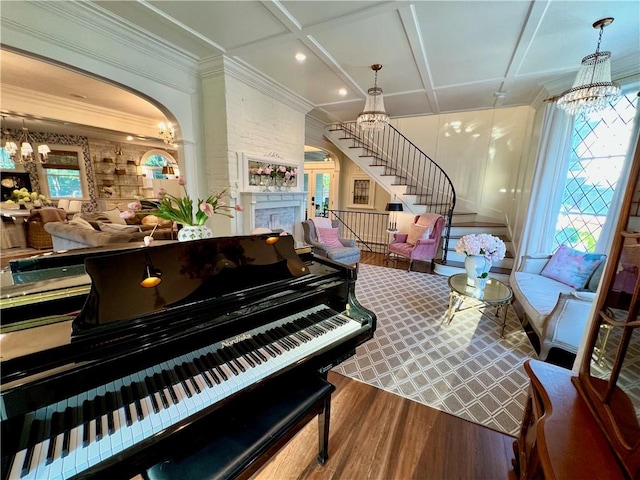 miscellaneous room featuring ornamental molding, coffered ceiling, an inviting chandelier, and wood-type flooring