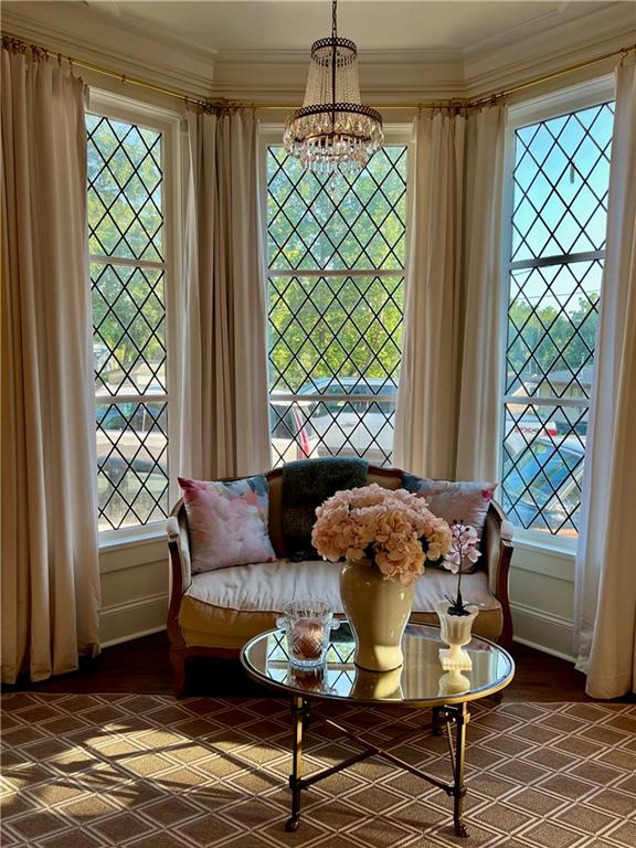 sitting room with ornamental molding, a notable chandelier, and a healthy amount of sunlight