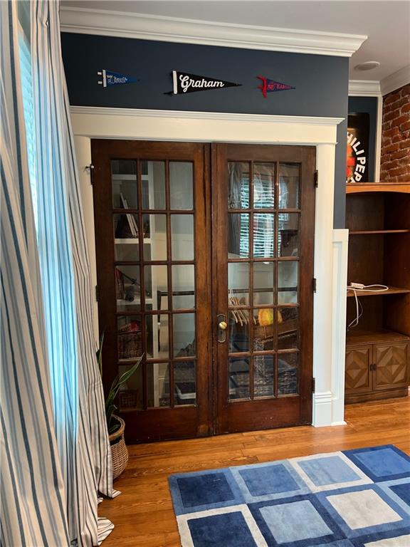 interior space featuring hardwood / wood-style floors, french doors, and crown molding