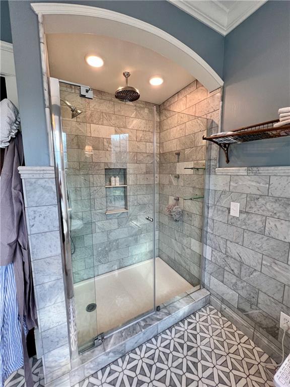 bathroom with ornamental molding, a shower with shower door, and tile flooring