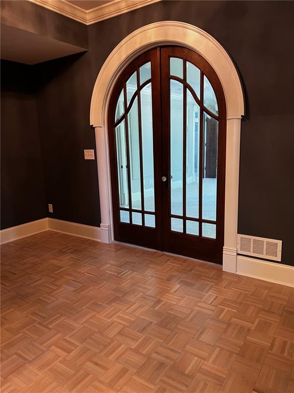 foyer with french doors, parquet floors, and crown molding