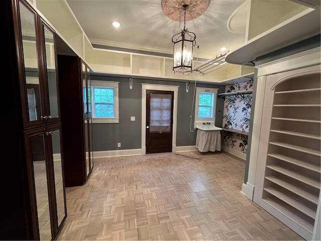 foyer entrance featuring parquet floors, crown molding, and an inviting chandelier