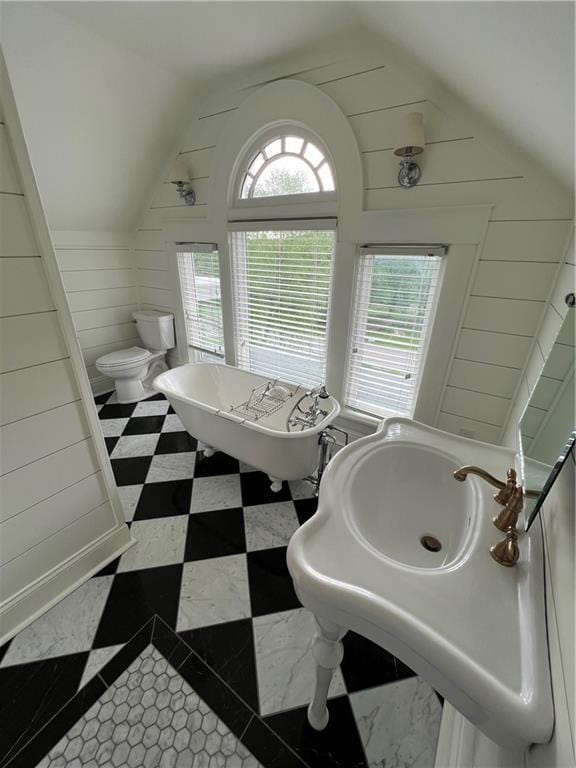 bathroom featuring lofted ceiling, a tub, toilet, and tile floors