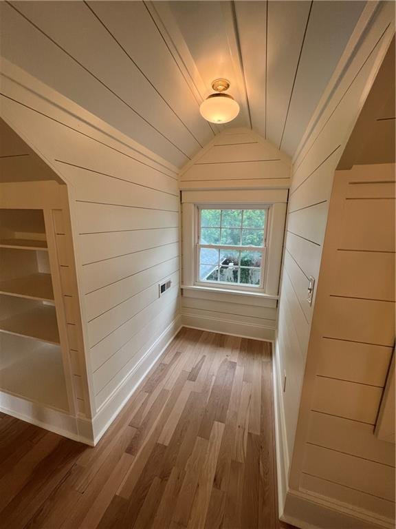 bonus room featuring built in features, lofted ceiling, hardwood / wood-style flooring, and wooden walls