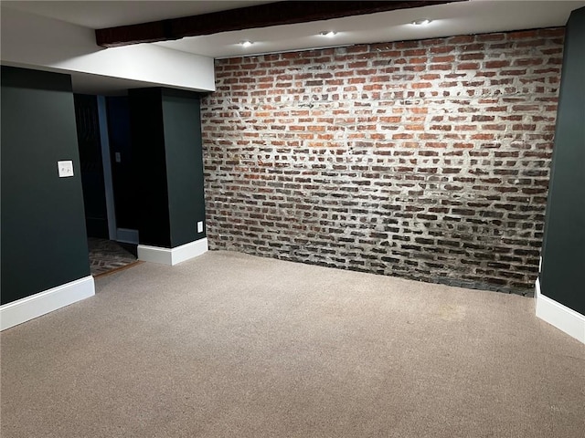 empty room with beam ceiling, brick wall, and carpet flooring