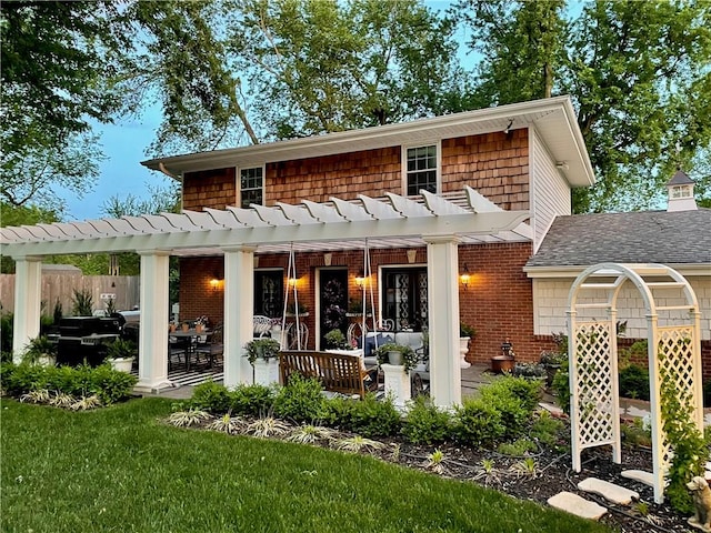 rear view of house featuring a patio area, a yard, and a pergola