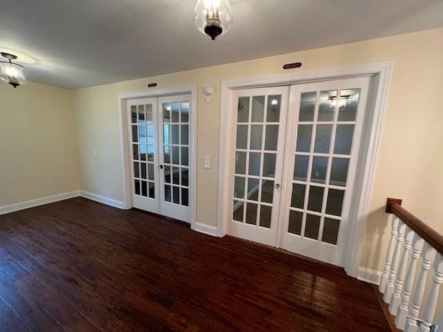 spare room featuring french doors and dark wood-type flooring