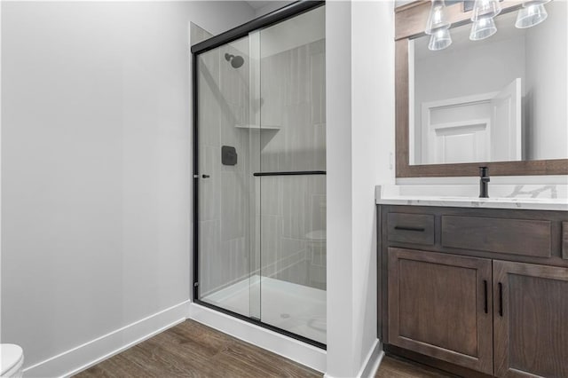 bathroom featuring vanity, a shower with shower door, toilet, and wood-type flooring